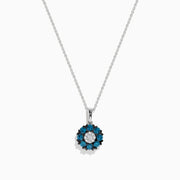 The Bella Bleu 14K White Gold Blue and White Diamond Flower Pendant features a circular floral design with a center cluster of white stones surrounded by sparkling blue and white diamonds.