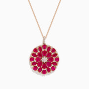The Ruby Royale 14K Rose Gold Ruby and Diamond Flower Pendant features a round floral design with rubies and diamond accents at the center and edges.
