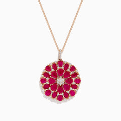 The Ruby Royale 14K Rose Gold Ruby and Diamond Flower Pendant features a round floral design with rubies and diamond accents at the center and edges.