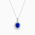 The Nahla Siri 14K White Gold Tanzanite and Diamond Pendant features an oval tanzanite stone encircled by a halo of sparkling diamonds, showcased on a white background.