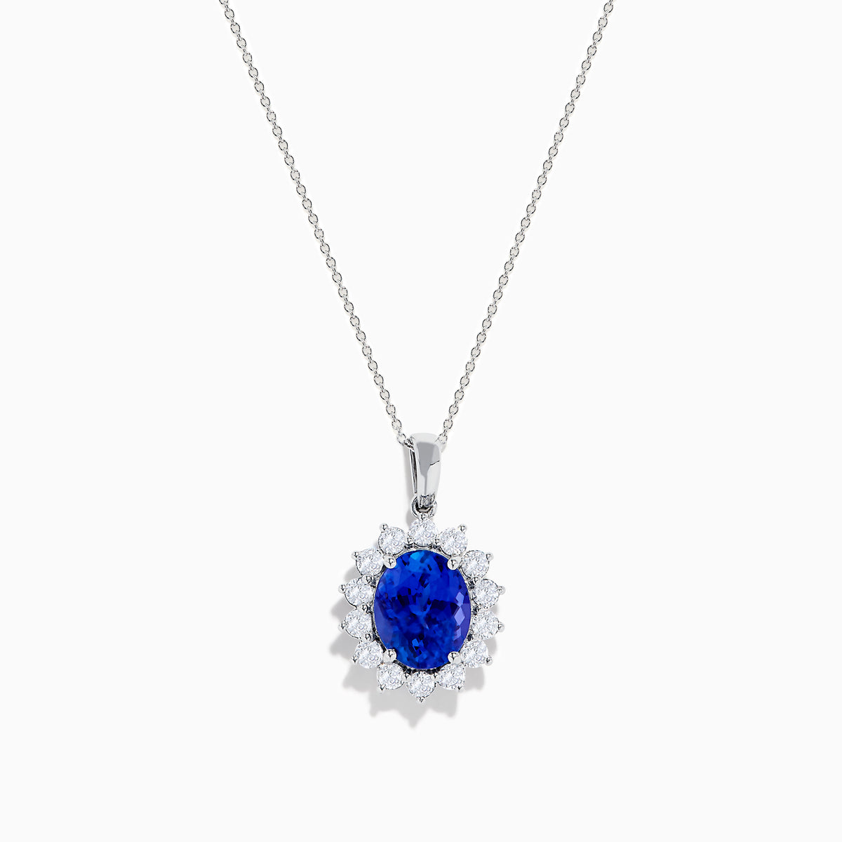 The Nahla Siri 14K White Gold Tanzanite and Diamond Pendant features an oval tanzanite stone encircled by a halo of sparkling diamonds, showcased on a white background.