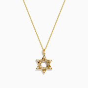 The 14K Yellow Gold Diamond Star of David Pendant features a shining diamond centerpiece and sparkling gemstones along the edges, set on a classic gold chain.