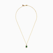 The 14K Yellow Gold Emerald and Diamond Halo Pendant features a rectangular green emerald, surrounded by round and baguette diamonds in a halo setting, all centrally suspended from a delicate gold chain.