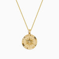 The D'Oro 14K Yellow Gold Diamond Compass Coin Pendant features a round medallion with a compass-inspired design, accented by a diamond at the center and suspended from a delicate yellow gold chain.