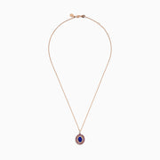 The 14K Rose Gold Pink Sapphire, Tanzanite, and Diamond Double Halo Pendant features an oval-shaped blue gemstone surrounded by pink sapphires, tanzanite, and diamonds on a delicate 14K rose gold chain attached at the top.