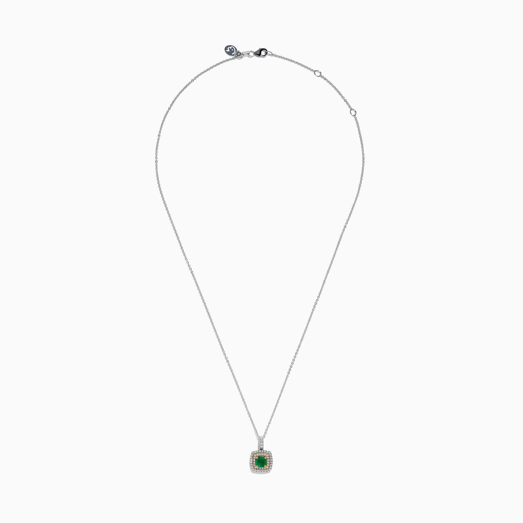 The 14K Two Tone Gold Emerald and Diamond Double Halo Pendant features a central green emerald surrounded by two rows of sparkling diamonds, all suspended from a delicate chain, showcased on a white background.
