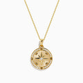 The 14K Yellow Gold Diamond Compass Rose Medallion Pendant features a round diamond compass design with a central gemstone and sparkling border, elegantly suspended from a delicate gold chain.
