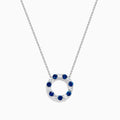 The Royale Bleu 14K white gold necklace features a circular eternity pendant with alternating blue and white sapphires, shown on a white background.
