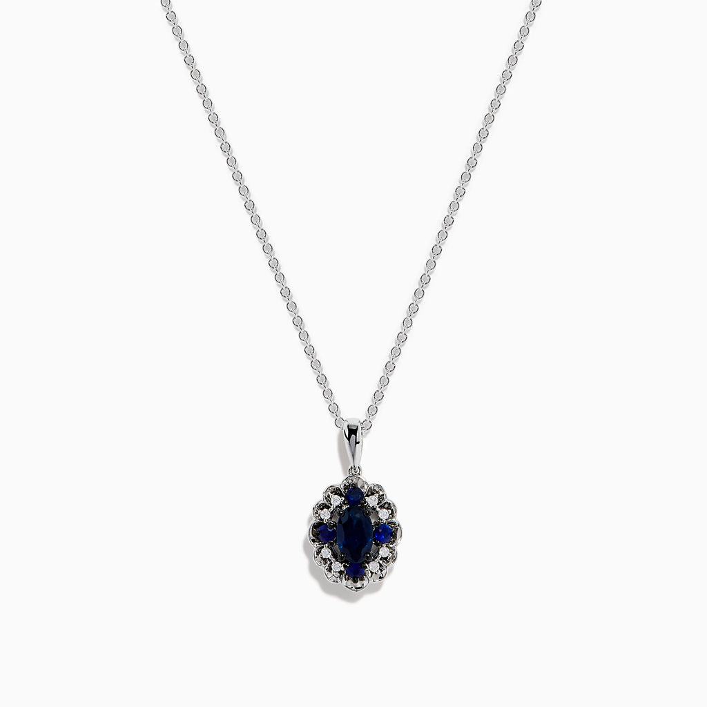 A 14K white gold Sapphire and Diamond Vintage Halo Pendant, featuring a large oval blue sapphire surrounded by smaller diamonds in a floral pattern, is displayed on a white background.