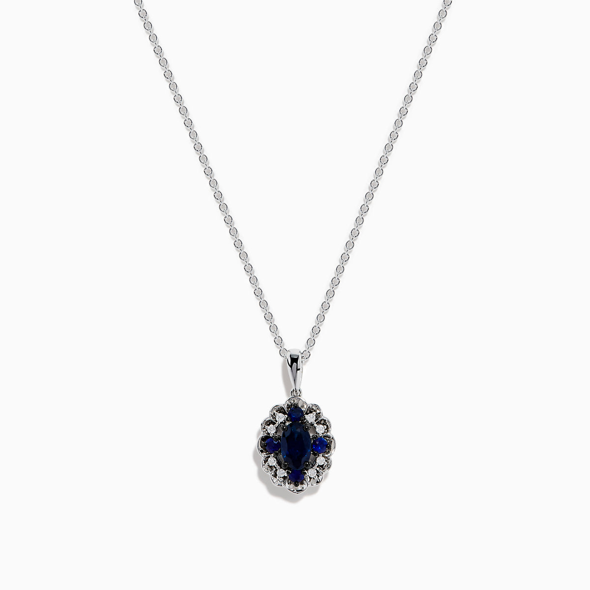 A 14K white gold Sapphire and Diamond Vintage Halo Pendant, featuring a large oval blue sapphire surrounded by smaller diamonds in a floral pattern, is displayed on a white background.