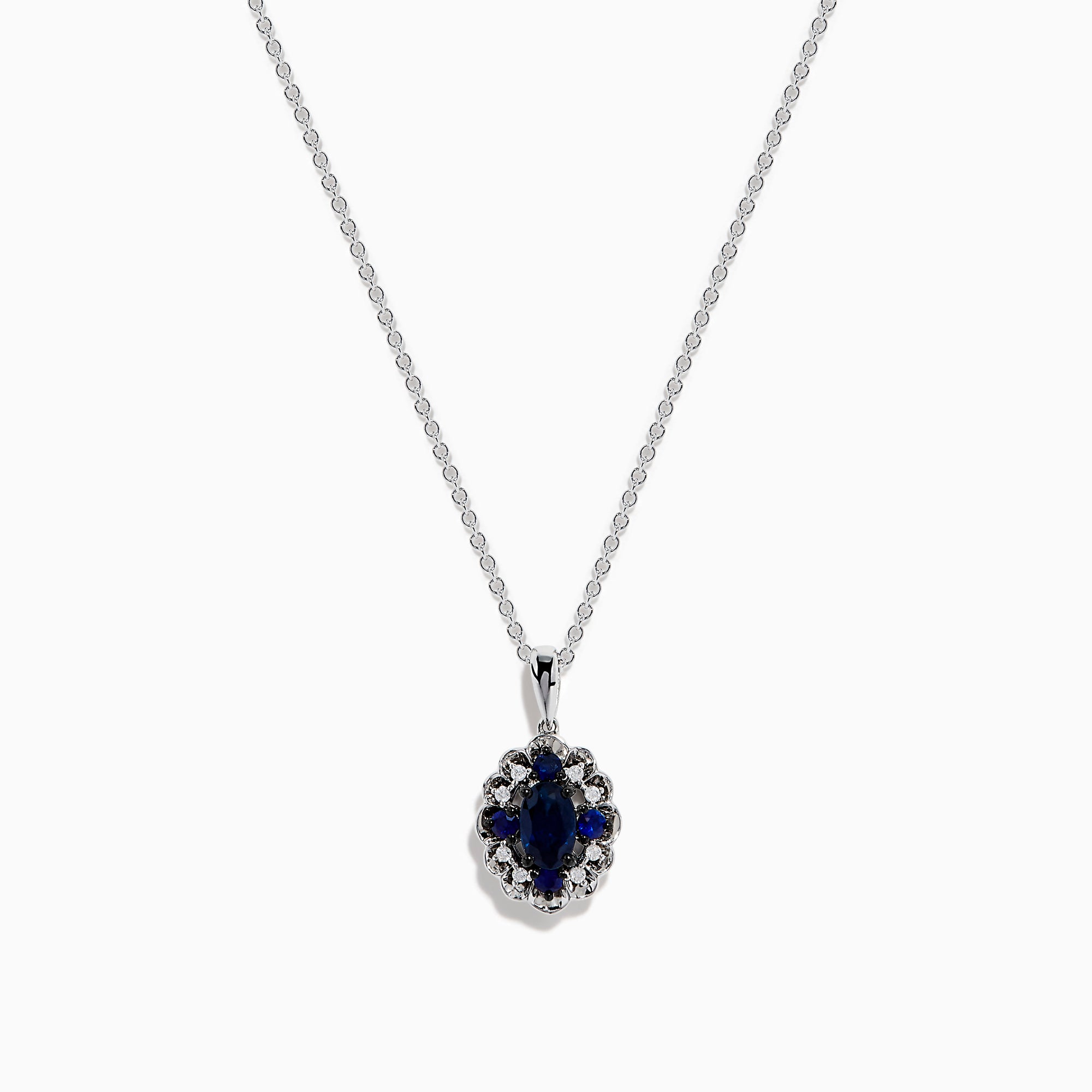 A 14K white gold Sapphire and Diamond Vintage Halo Pendant, featuring a large oval blue sapphire surrounded by smaller diamonds in a floral pattern, is displayed on a white background.