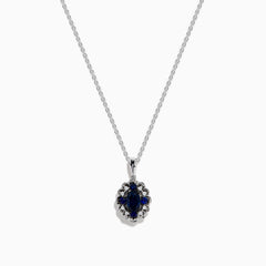 A 14K white gold Sapphire and Diamond Vintage Halo Pendant, featuring a large oval blue sapphire surrounded by smaller diamonds in a floral pattern, is displayed on a white background.