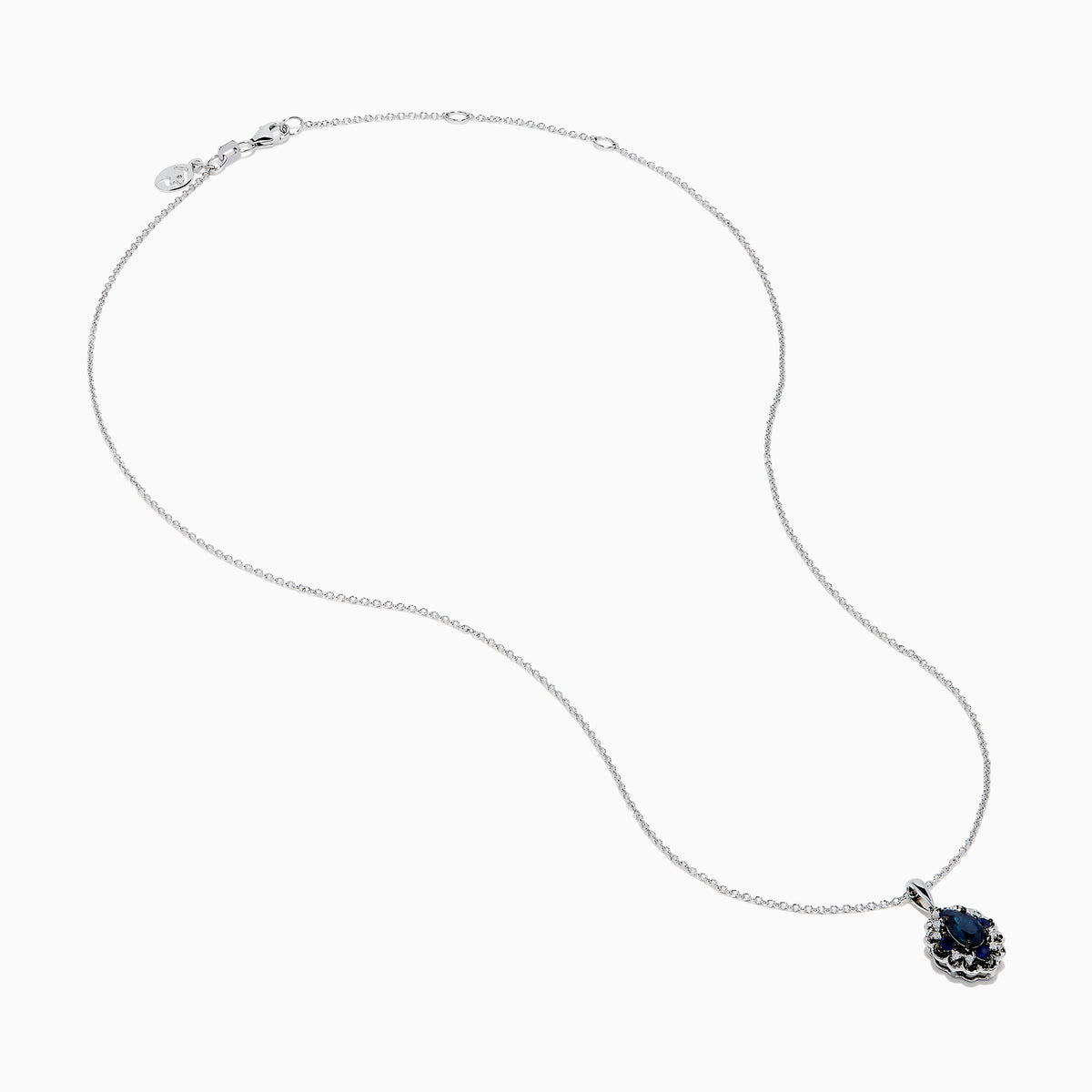 A 14K white gold Sapphire and Diamond Vintage Halo Pendant, featuring a large oval blue sapphire surrounded by smaller diamonds in a floral pattern, is displayed on a white background.