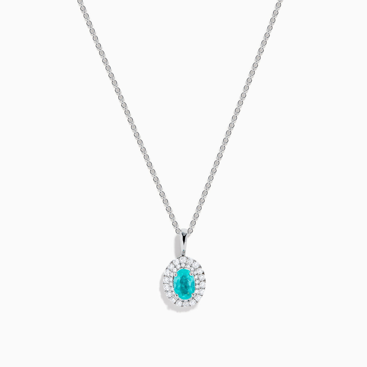 An 18K White Gold Paraiba and Diamond Pendant with an oval Paraiba gemstone and a halo of diamonds hangs from a delicate chain, shown against a plain white background.