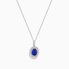 The Nahla Siri 14K White & Rose Gold Tanzanite and Diamond Pendant features an oval tanzanite surrounded by a double halo of diamonds, all set on a delicate silver chain and photographed against a white background.