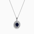The Royal Bleu 14K White Gold Sapphire & Diamond Halo Pendant features a vibrant sapphire framed by two rows of sparkling white diamonds, all set in a chain necklace against a plain white background.