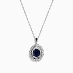 The Royal Bleu 14K White Gold Sapphire & Diamond Halo Pendant features a vibrant sapphire framed by two rows of sparkling white diamonds, all set in a chain necklace against a plain white background.
