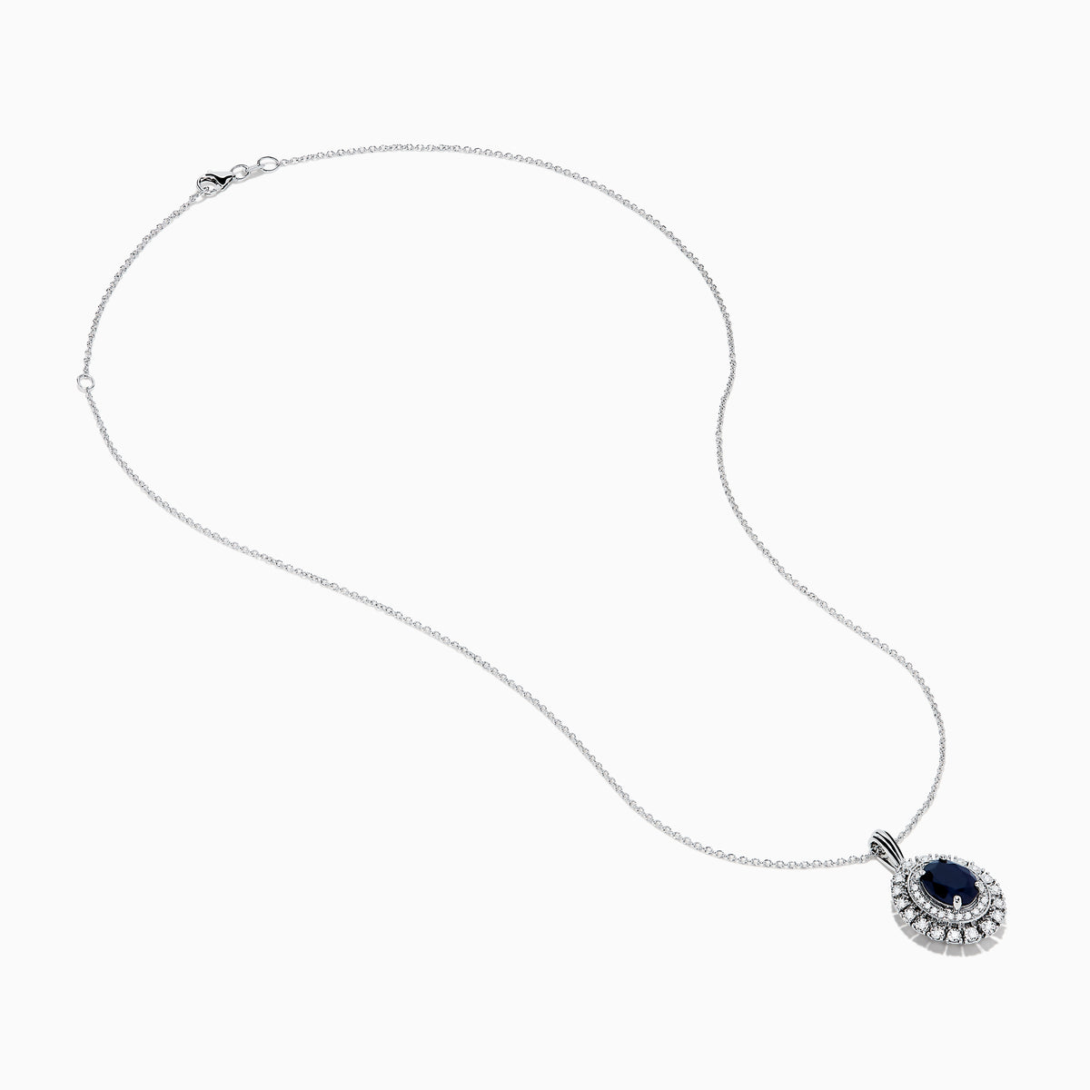 The Royal Bleu 14K White Gold Sapphire & Diamond Halo Pendant features a vibrant sapphire framed by two rows of sparkling white diamonds, all set in a chain necklace against a plain white background.
