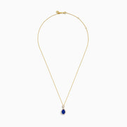 The Nahla Siri 14K Yellow Gold Tanzanite and Diamond Pendant features a teardrop blue tanzanite surrounded by white diamonds, plus a circular diamond accent above the main stone.