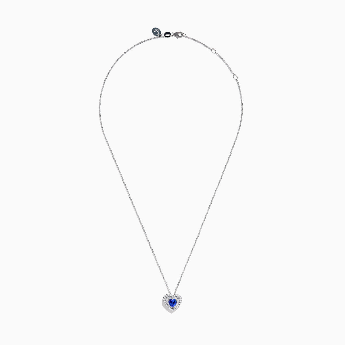 The Nahla Siri 14K White Gold Tanzanite and Diamond Heart Pendant showcases a vivid tanzanite at its center, encircled by sparkling diamonds, all set in white gold and displayed against a plain white background.