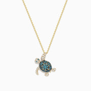 The Seaside 14K Yellow Gold Blue and White Diamond Turtle Pendant features sparkling blue and white diamonds on the shell, head, and flippers of a turtle, set on a gold chain against a plain white background.