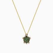 The 14K Yellow Gold Tsavorite and Diamond Turtle Pendant features a turtle-shaped design with a shell adorned in vibrant green tsavorites and sparkling diamonds on its head and feet, set against a plain white background.