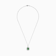 A 14K white gold pendant featuring an oval emerald, surrounded by a double halo of sparkling diamonds.