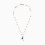 The Safari 14k Yellow Gold Emerald and Sapphire Humming Bird Pendant features a hummingbird-shaped design with emerald and sapphire accents, shown against a white background.
