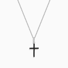 The Novelty 14K White Gold Black and White Diamond Cross Pendant features black stones and a single clear stone at the top, shown on a silver chain against a plain white background.