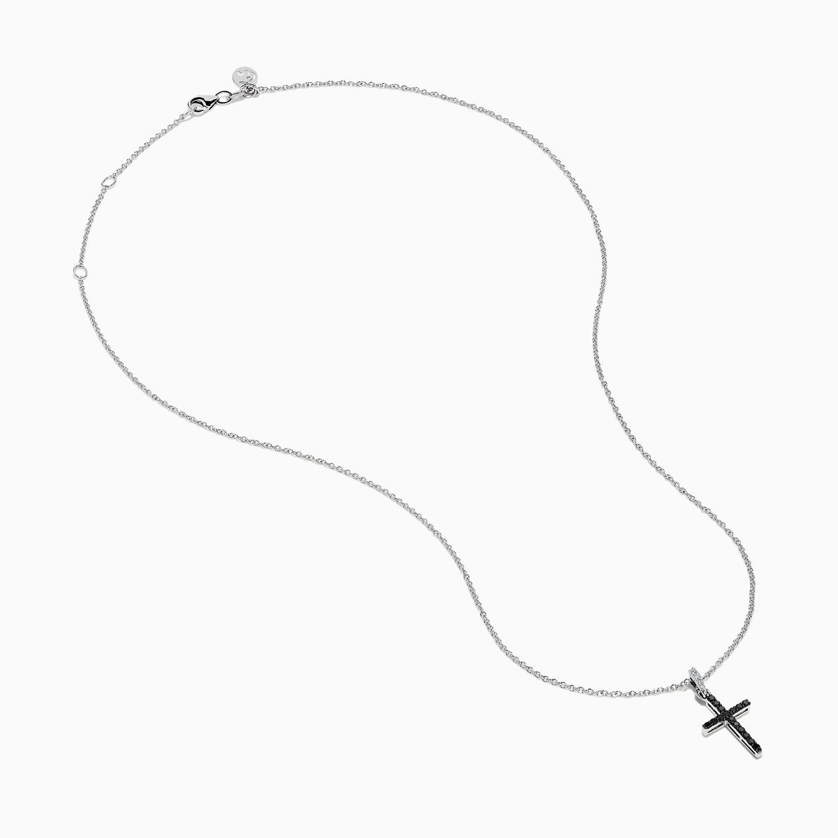 The Novelty 14K White Gold Black and White Diamond Cross Pendant features black stones and a single clear stone at the top, shown on a silver chain against a plain white background.