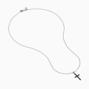 The Novelty 14K White Gold Black and White Diamond Cross Pendant features black stones and a single clear stone at the top, shown on a silver chain against a plain white background.