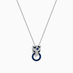 The Signature 14K White Gold Blue Sapphire and Diamond Panther Pendant showcases a diamond-studded panther head with blue and white gemstones, gripping a vivid blue sapphire pendant ring in its mouth.