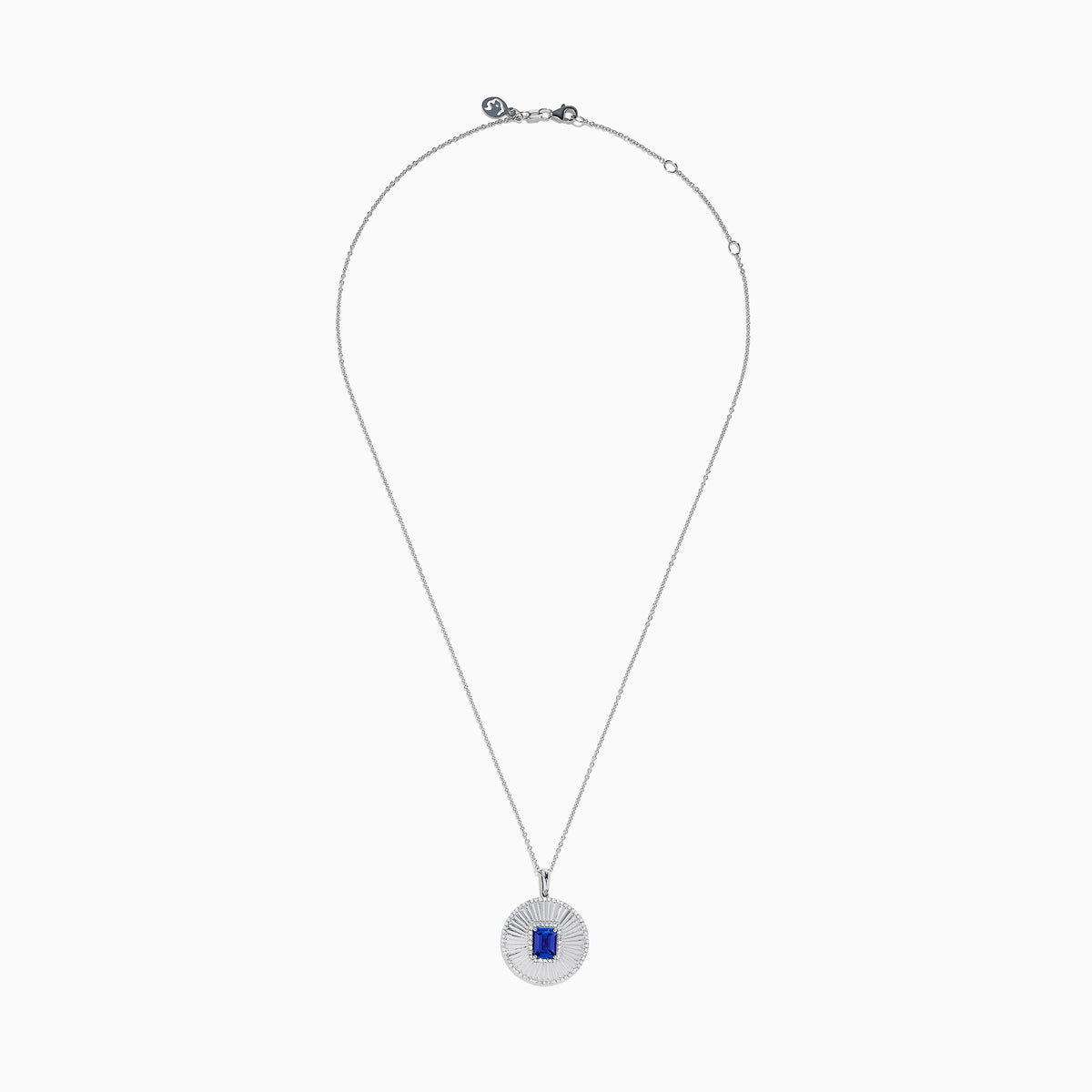 The 14K White Gold Tanzanite and Diamond Fluted Circle Pendant features a round diamond-accented design with a radiant motif and a central emerald-cut blue tanzanite stone.