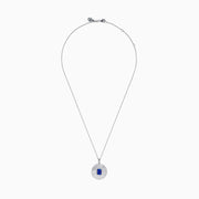 The 14K White Gold Tanzanite and Diamond Fluted Circle Pendant features a round diamond-accented design with a radiant motif and a central emerald-cut blue tanzanite stone.