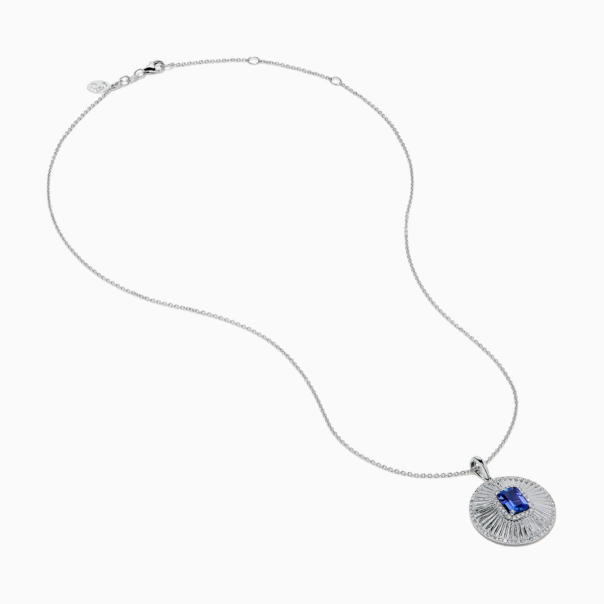 The 14K White Gold Tanzanite and Diamond Fluted Circle Pendant features a round diamond-accented design with a radiant motif and a central emerald-cut blue tanzanite stone.