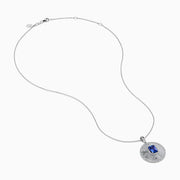 The 14K White Gold Tanzanite and Diamond Fluted Circle Pendant features a round diamond-accented design with a radiant motif and a central emerald-cut blue tanzanite stone.
