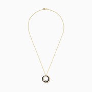A delicate 14K yellow gold necklace with a round pendant showcasing interlocking gold and black diamond circles, accented by a sparkling diamond, displayed on a plain white background.