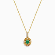 The 14K Yellow Gold Emerald and Diamond Filigree Halo Pendant features an elegant oval green emerald encircled by sparkling diamonds, with additional diamond accents on the bail for added brilliance.