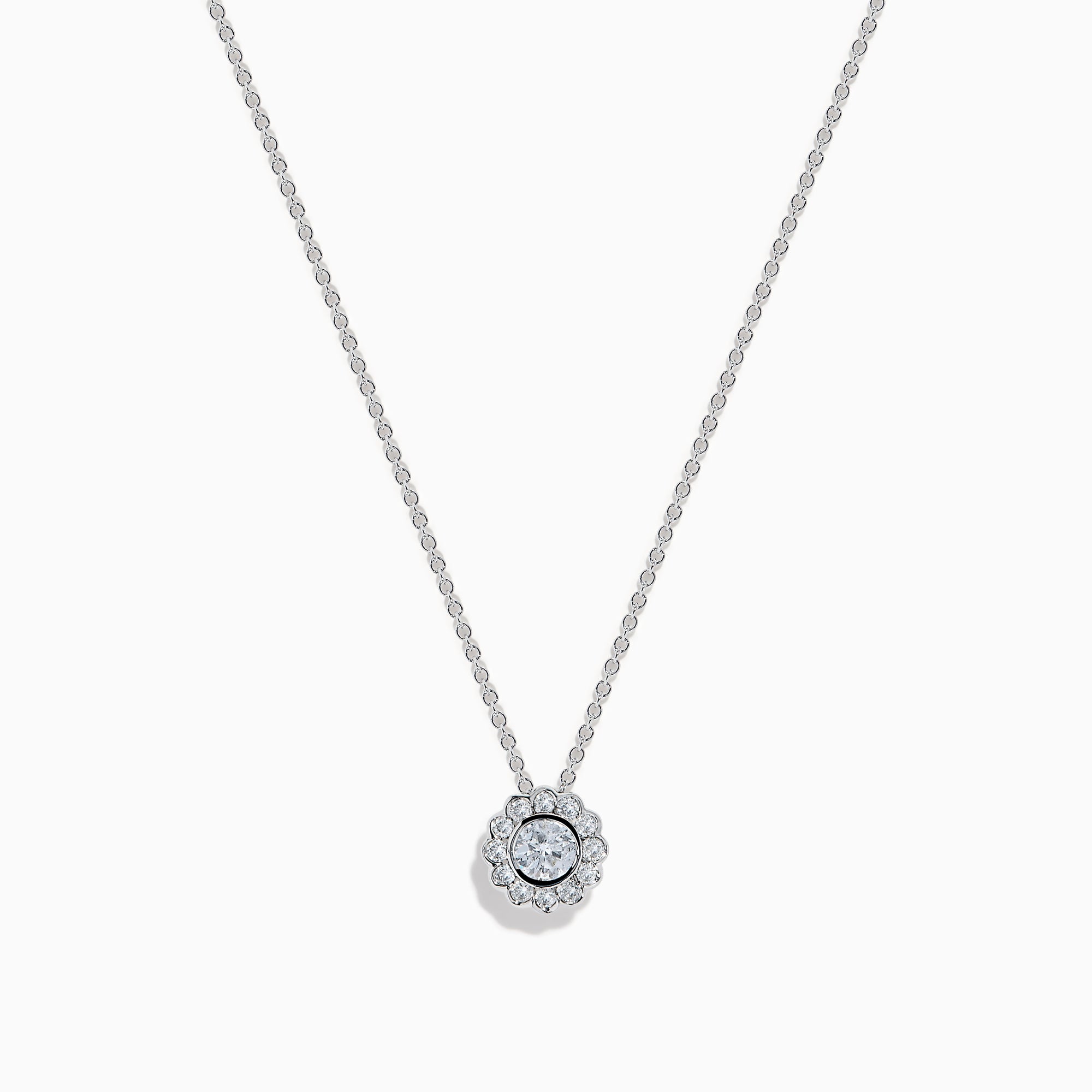 The 14K White Gold Diamond Bezel Halo Pendant features a delicate white gold chain with a round, flower-like diamond pendant, showcasing a central diamond surrounded by a halo of smaller diamonds.