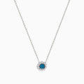 The Bella Bleu 14K White Gold Pendant showcases a round blue and white diamond centerpiece, accented by a halo of 0.60 TCW diamonds, elegantly presented on a white background.