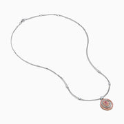 The 18K Two Tone Gold White and Pink Diamond Pendant necklace features a double-chain design with a round pendant of concentric circles, set with white and pink diamonds and topped by a single white gemstone.