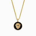 The Mens 14K Yellow Gold Black Diamond Lion Head Pendant features a detailed lion head on a black textured background, red eyes, and hangs from a shiny medium-thick chain for an impressive look.