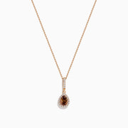 The 14K Rose Gold Pear Halo Brown and White Diamond Pendant features a teardrop-shaped brown and white diamond centerpiece, bordered with sparkling clear stones and accented by a vertical row of clear stones above.