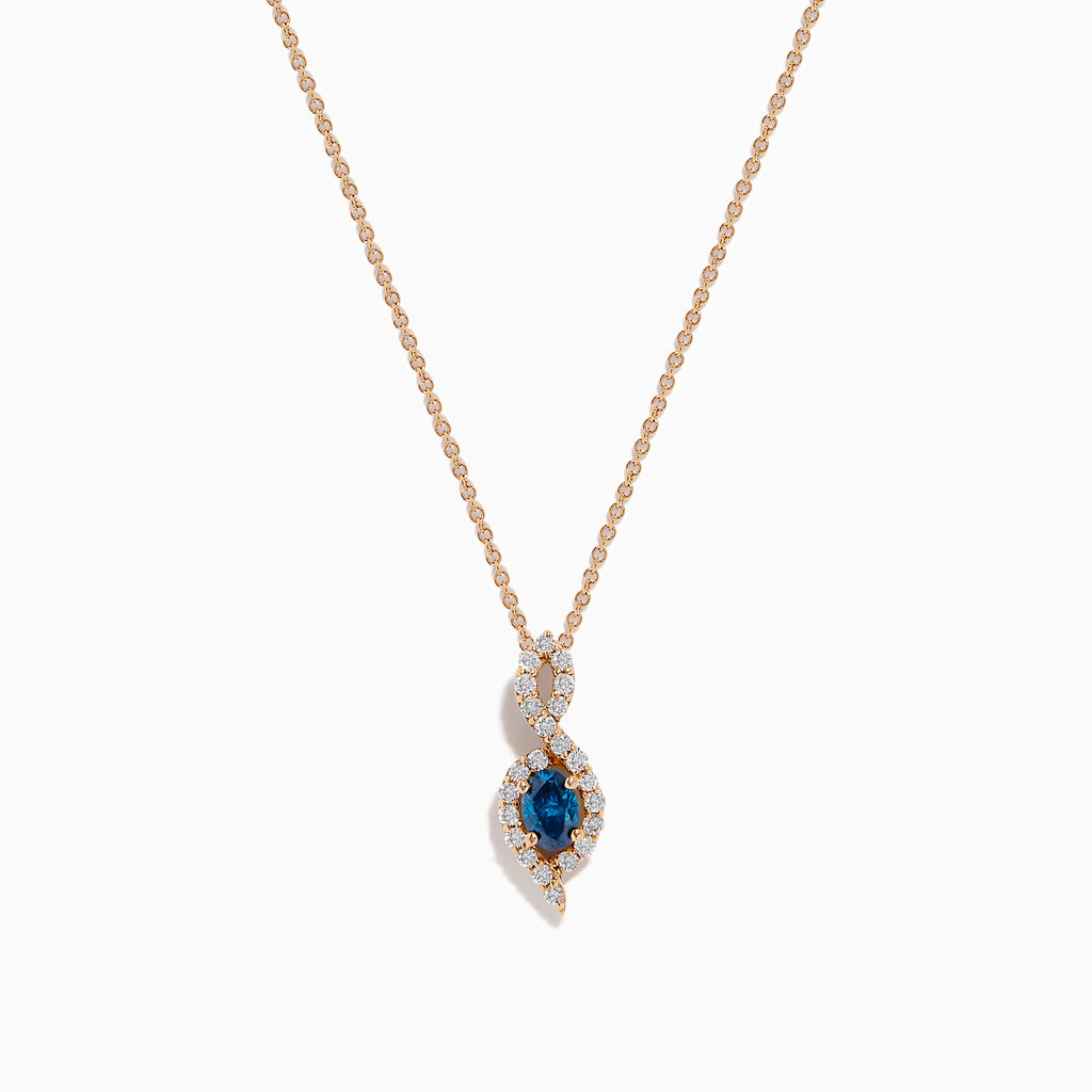 The 14K Rose Gold Blue and White Diamond Pendant features a deep blue oval gemstone with sparkling blue and white diamonds set in a twisting, teardrop-shaped design.