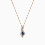 The 14K Rose Gold Blue and White Diamond Pendant features a deep blue oval gemstone with sparkling blue and white diamonds set in a twisting, teardrop-shaped design.