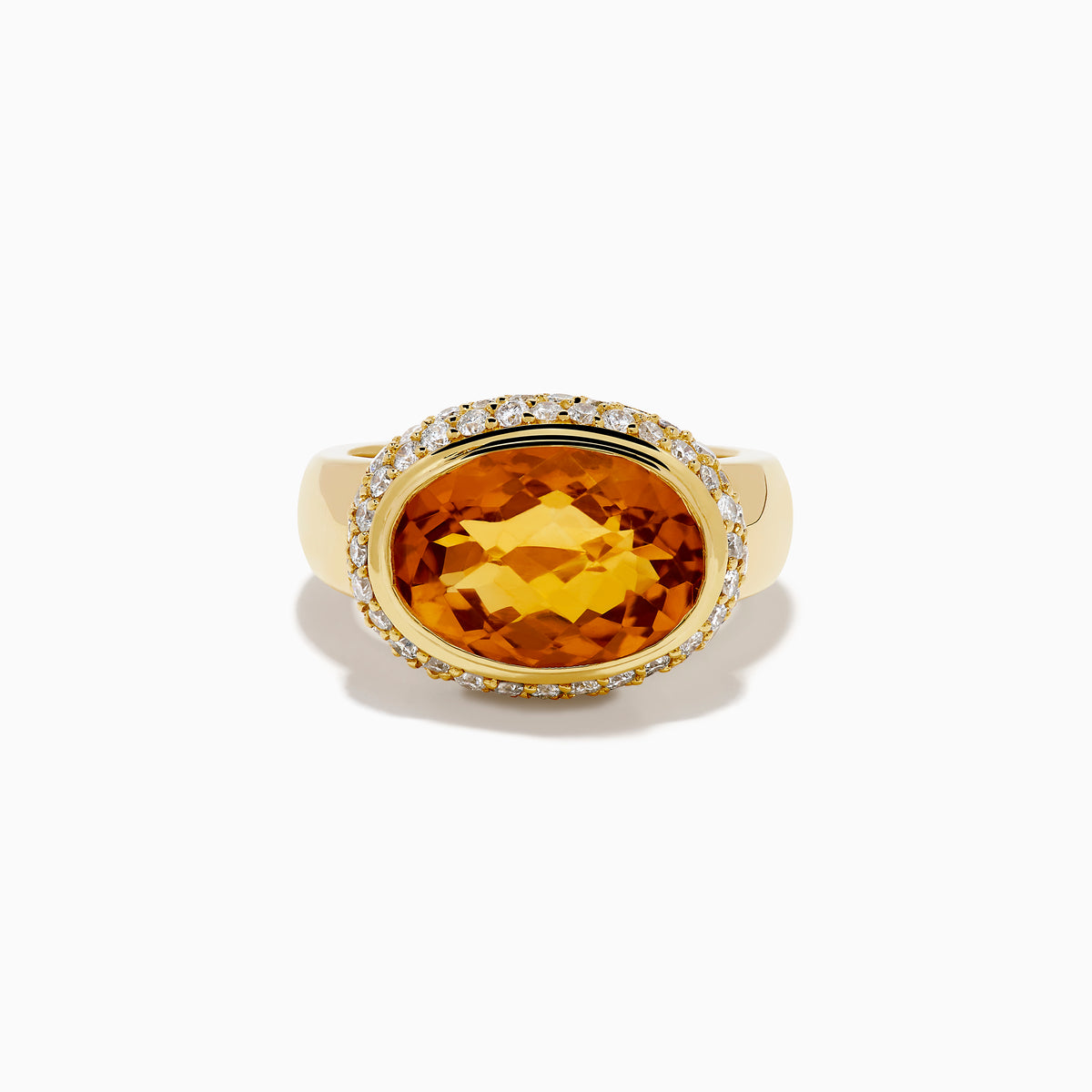 An 18K yellow gold ring featuring an east-west set oval citrine centerpiece, accented by a bezel halo of sparkling diamonds.