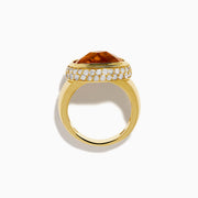 An 18K yellow gold ring featuring an east-west set oval citrine centerpiece, accented by a bezel halo of sparkling diamonds.