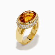An 18K yellow gold ring featuring an east-west set oval citrine centerpiece, accented by a bezel halo of sparkling diamonds.