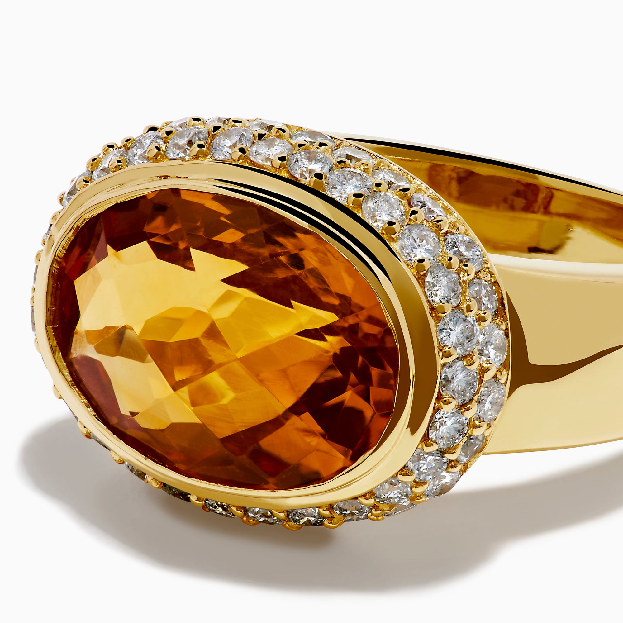 An 18K yellow gold ring featuring an east-west set oval citrine centerpiece, accented by a bezel halo of sparkling diamonds.