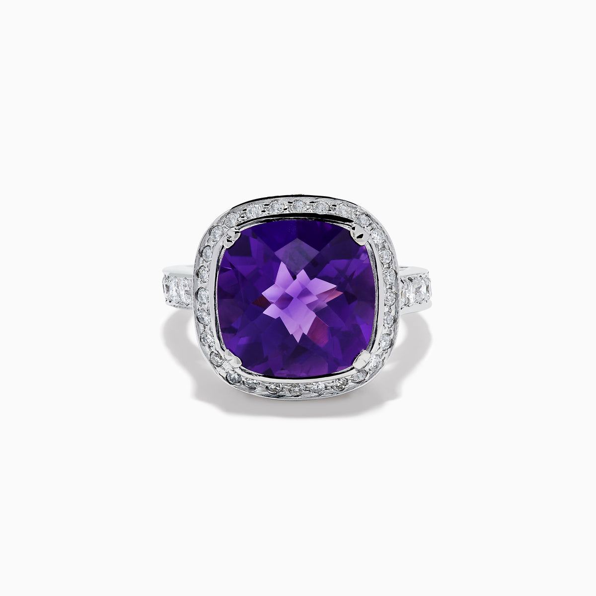 The 18K White Gold Amethyst and Diamond Cushion Halo Cocktail Ring features a striking cushion-cut amethyst center, a sparkling diamond halo, and clear stones on the band, elegantly displayed against a white background.